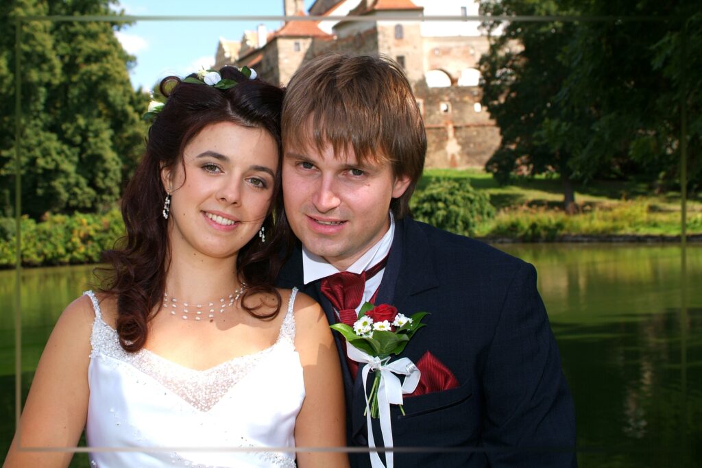 Detail novomanželů před hradem a vodní hladinou